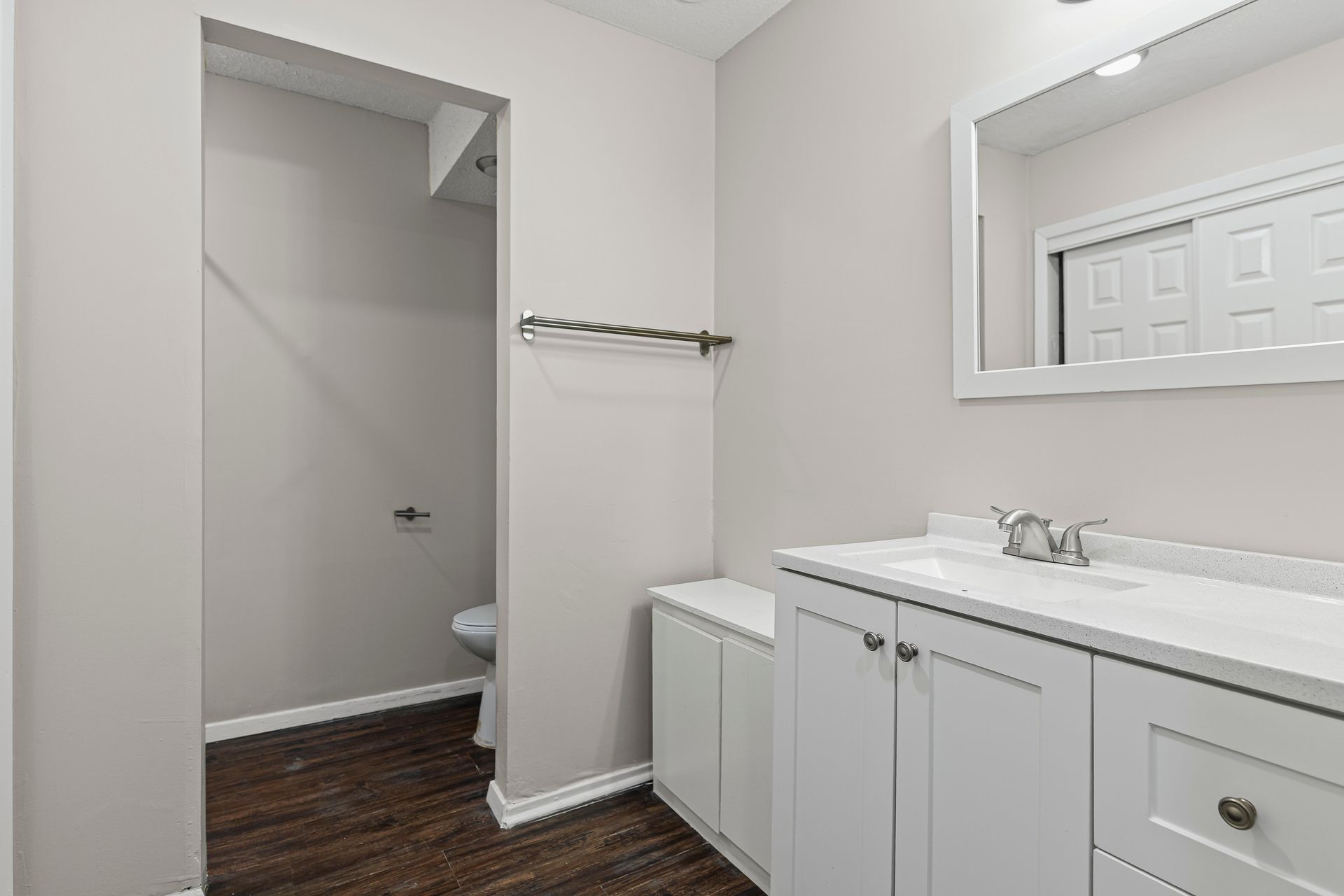 Bathroom with white vanity, toilet room, and dark wood floor.