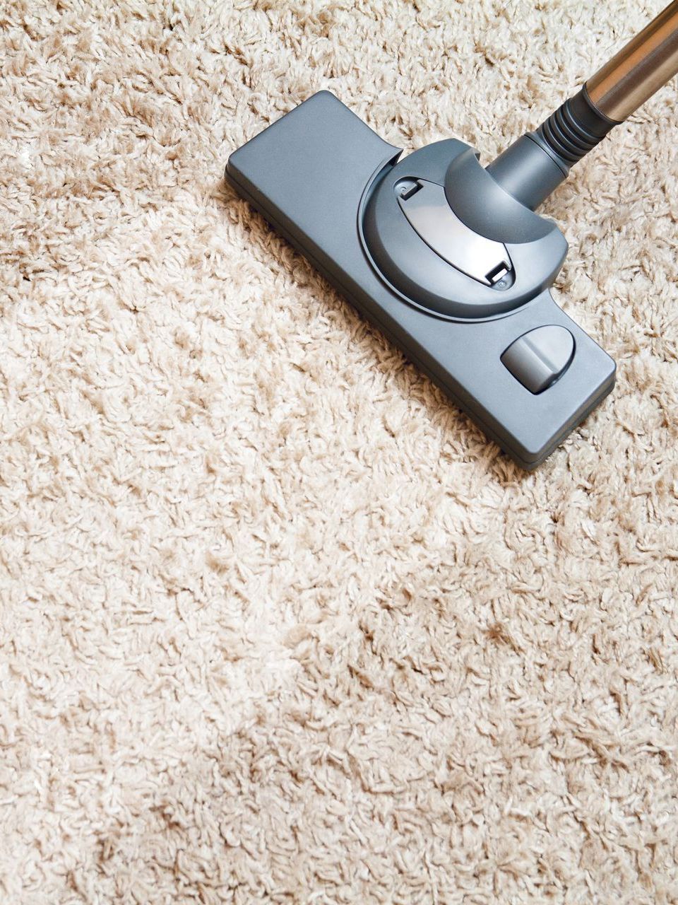 A vacuum cleaner is being used to clean a carpet.