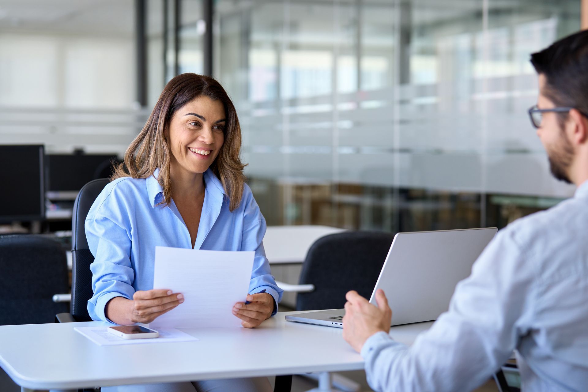 A smiling professional female or employer having a job interview meeting with a male candidate.