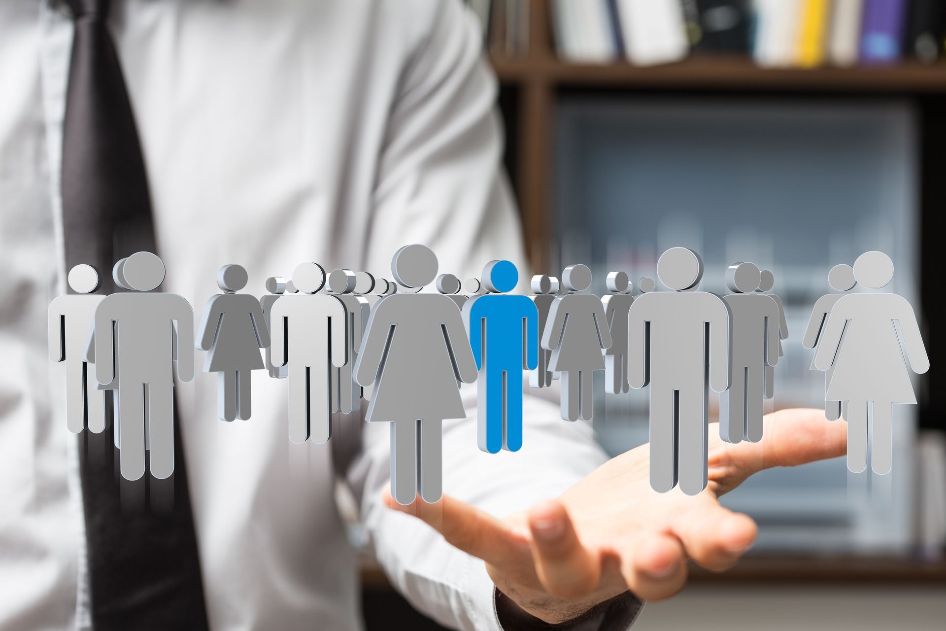Highlighted blue human figure among gray people icons hovering above an open hand.