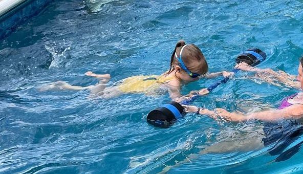A group of children are swimming in a swimming pool.
