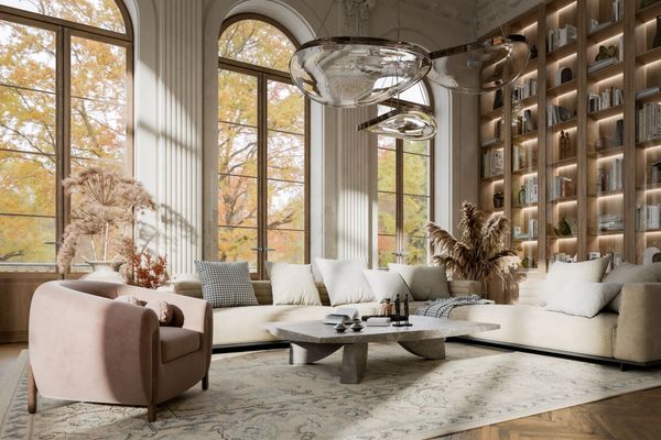 Cozy living room with large arched windows, a beige sectional sofa, a pink armchair, and a built-in bookshelf.