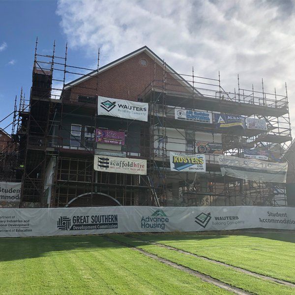 A large building with scaffolding around it and a fence in front of it.