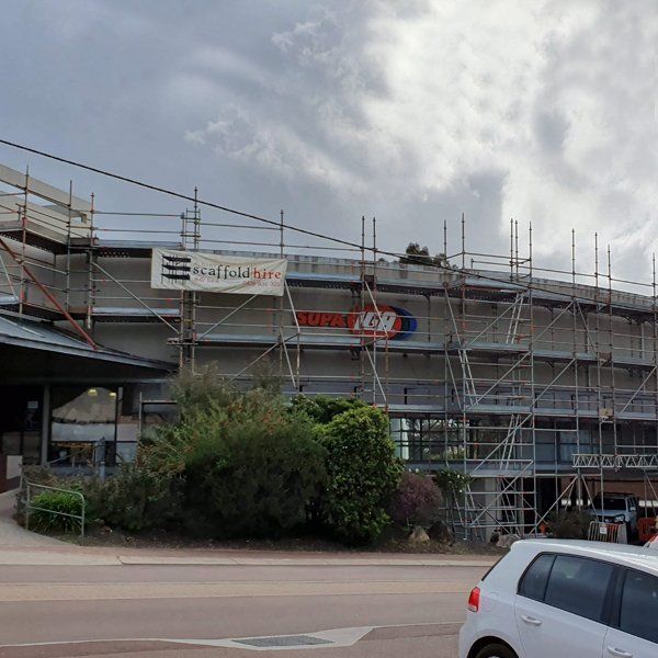 A white car is parked in front of a building under construction