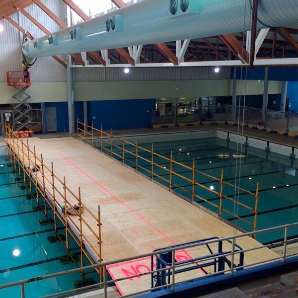A large indoor swimming pool with a wooden walkway leading to it
