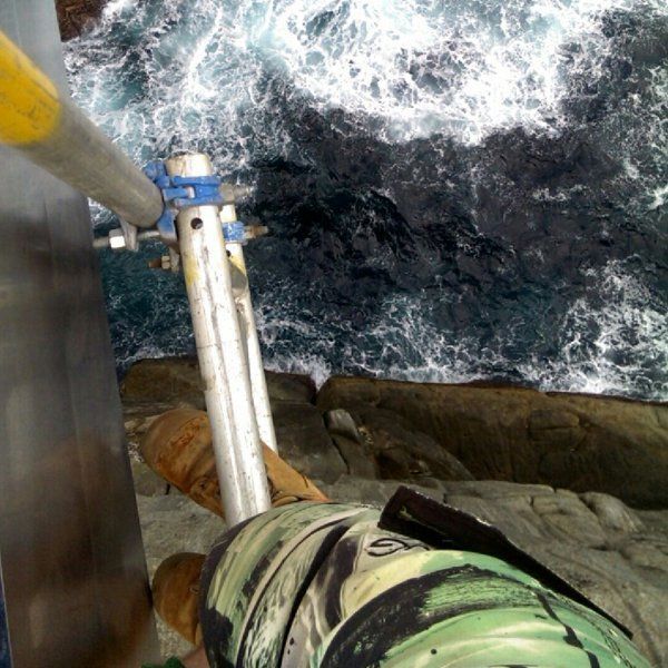 A person laying on a rock looking out over the ocean
