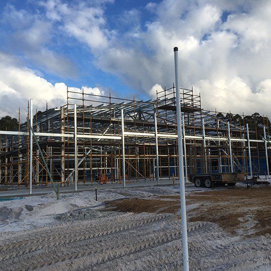 A large building under construction with scaffolding and a truck parked in front of it.