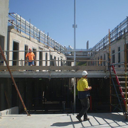 A man in a yellow shirt is walking on a construction site