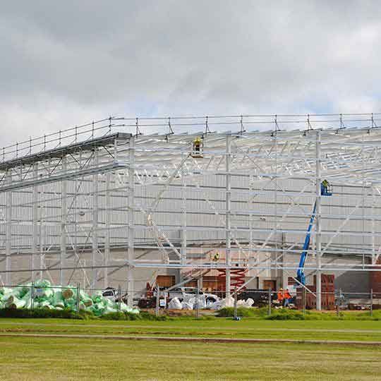 A large metal structure is being built in a field.