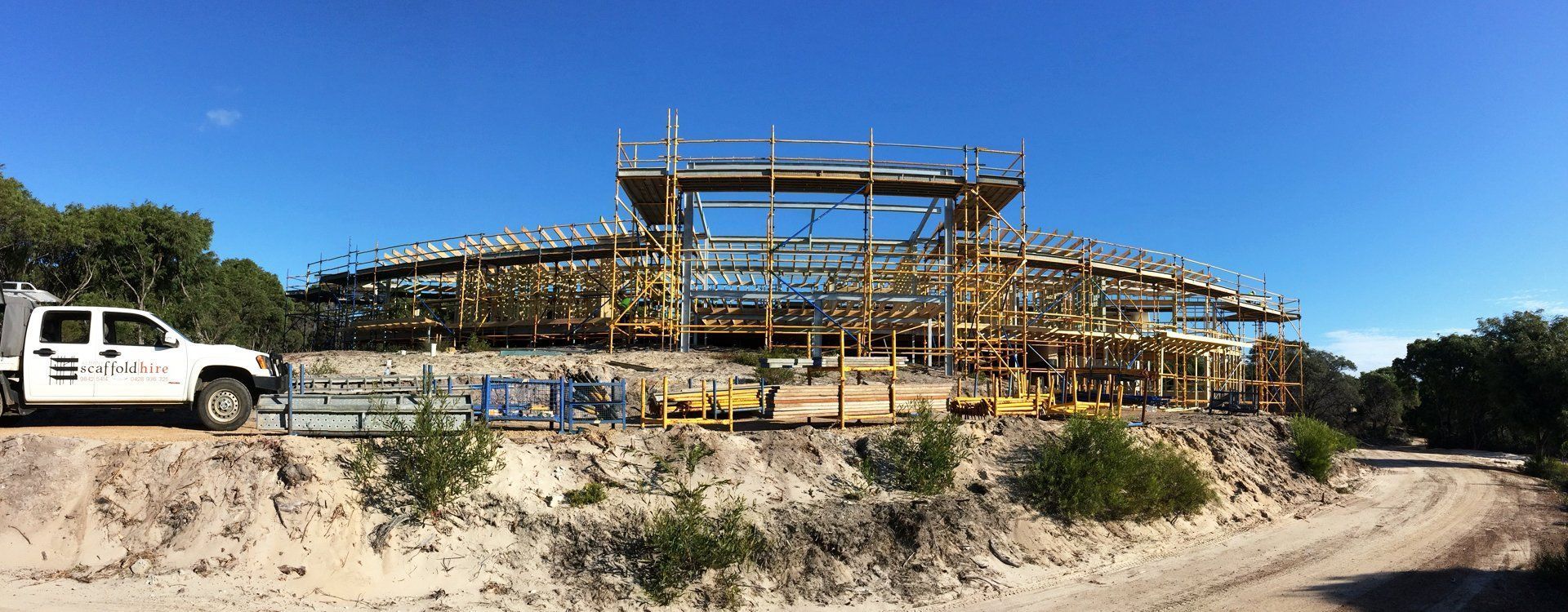 A white truck is parked in front of a large building under construction.