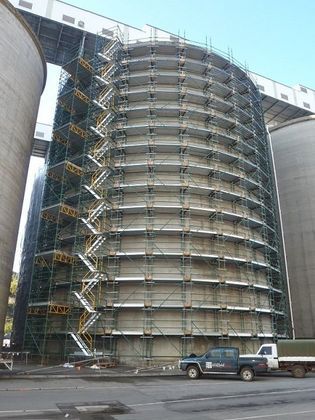A large building with scaffolding around it and a truck parked in front of it.