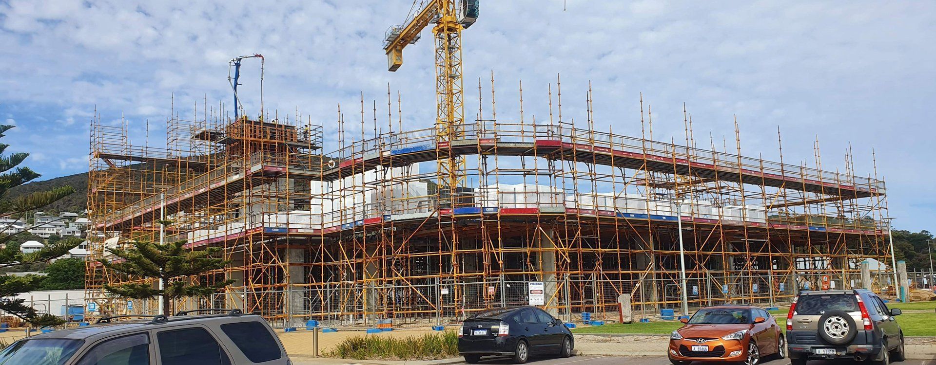 A large building is being built with scaffolding and a crane.