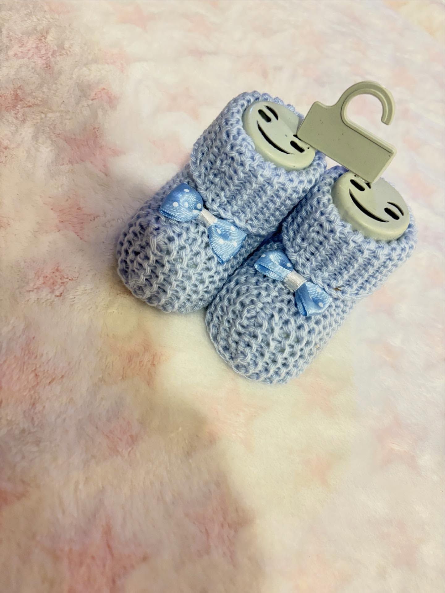 Scarpine blu per neonati lavorate a maglia con nastro e cartellino del prezzo.