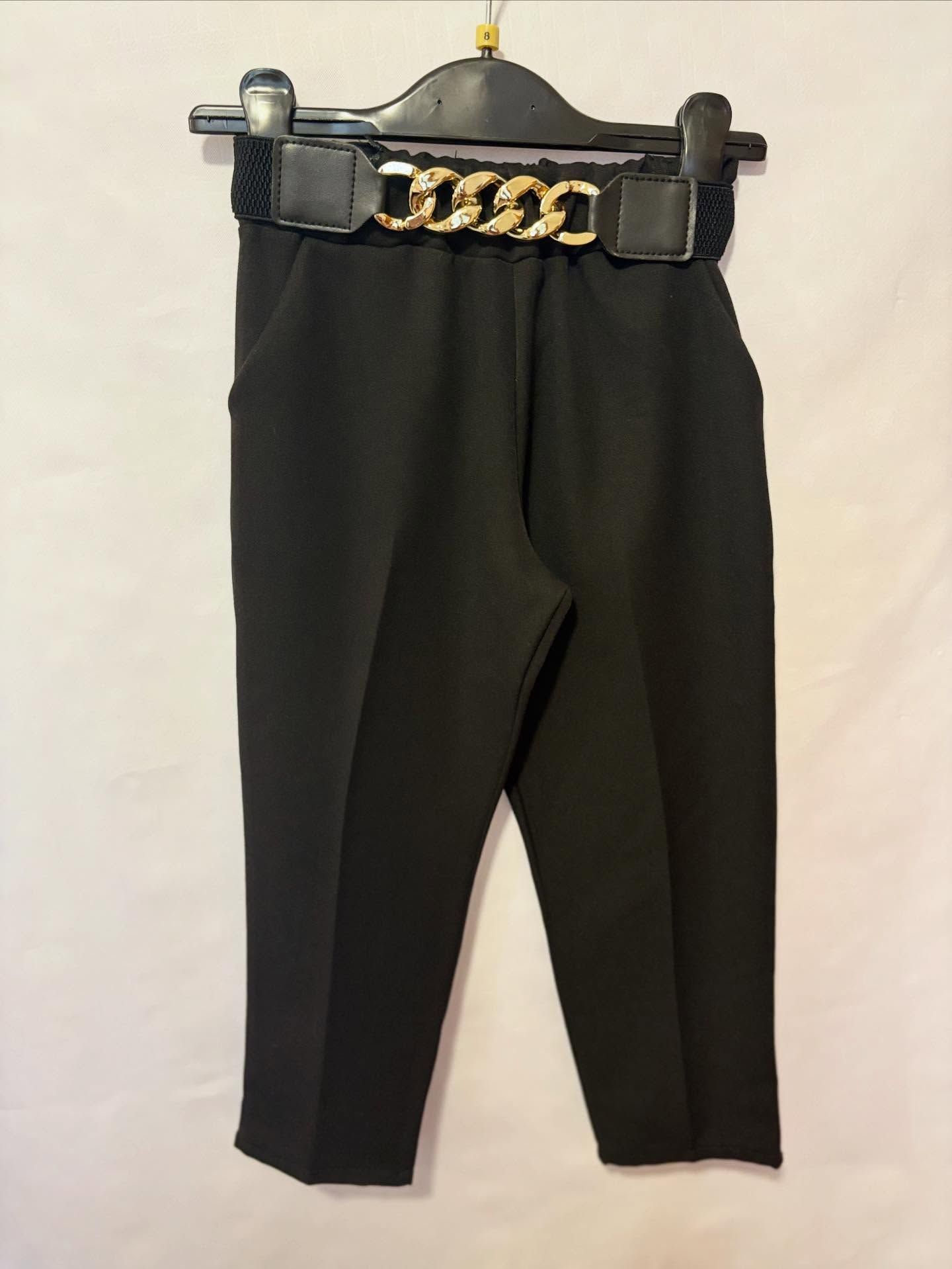 Pantaloni neri corti con cintura a catena dorata appesa a una gruccia.