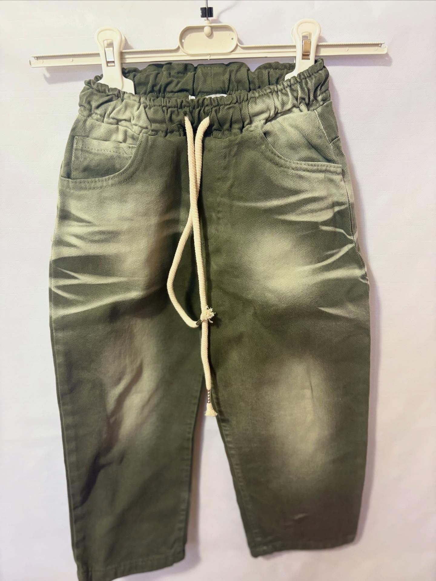 Pantaloni di jeans verdi con elastico in vita e coulisse, appesi a una gruccia.