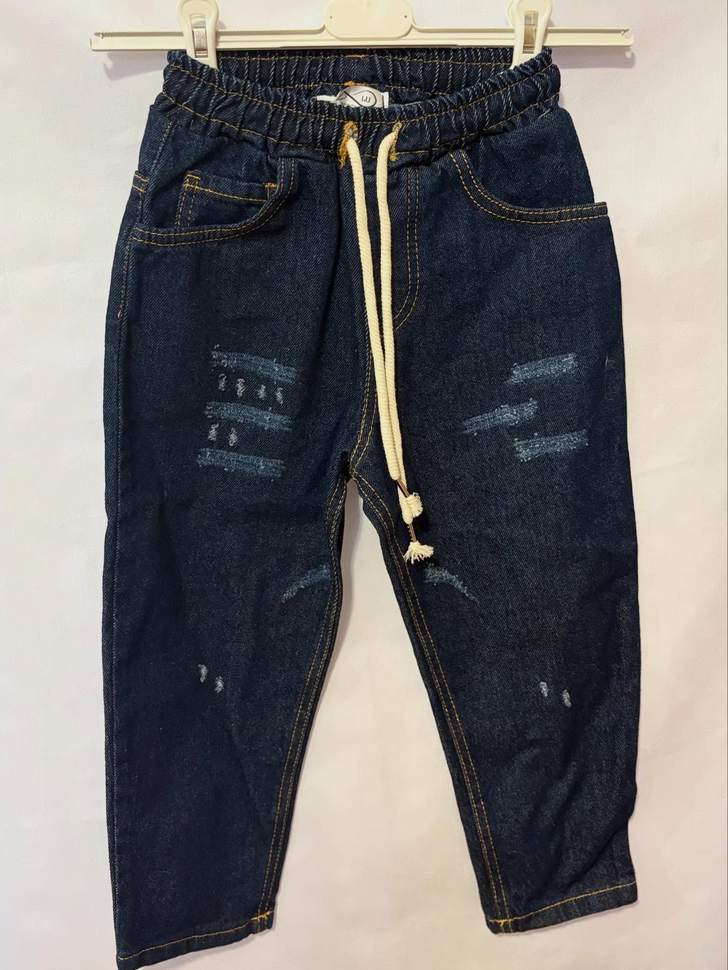 Pantaloni in denim blu scuro con coulisse in vita e dettagli rovinati.