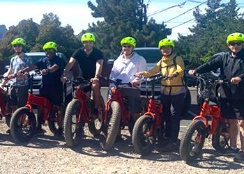 A group of people are standing next to each other on bicycles.