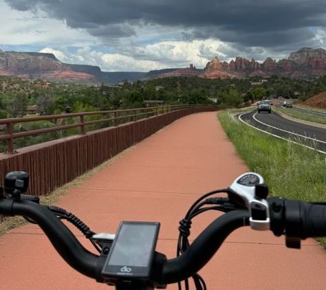 A person riding a bike on a path with mountains in the background