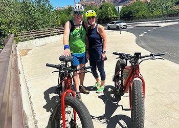 A man and a woman are standing next to two bicycles.