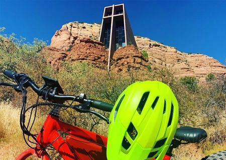 A yellow helmet is sitting on the handlebars of a red bicycle.