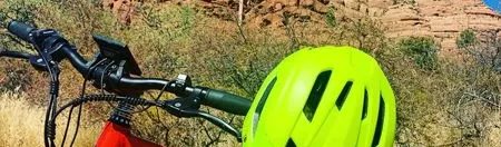 A yellow helmet is sitting on the handlebars of a red bicycle.