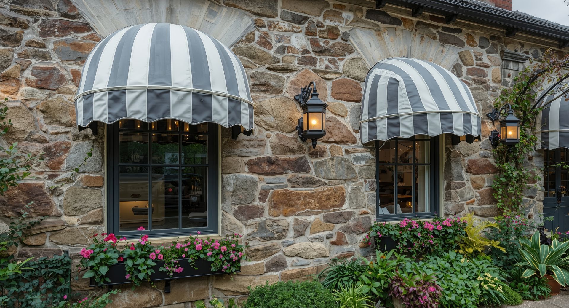Stone storefront with striped awnings, lanterns, and flower boxes along a rustic wall