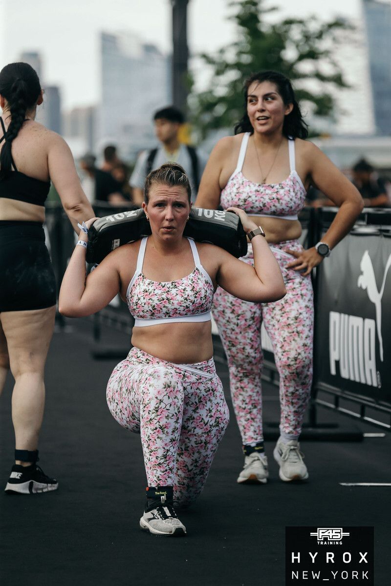 A man is lifting dumbbells over his head in a gym