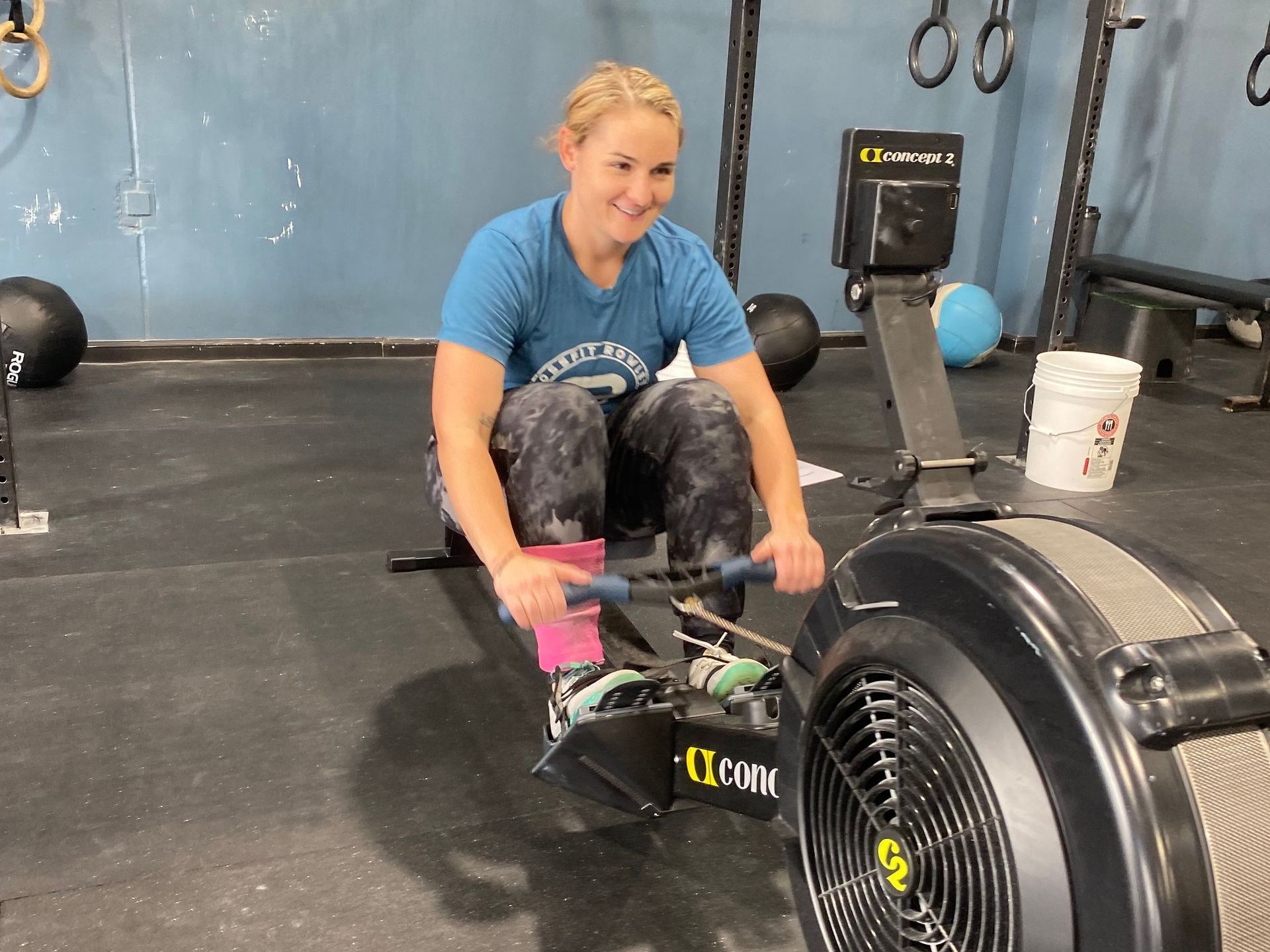 A woman is riding a rowing machine in a gym.