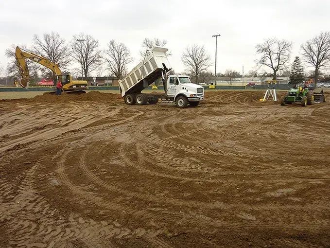A dump truck is being loaded with dirt on a construction site