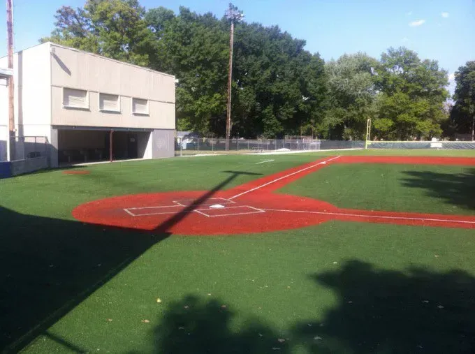 A baseball field with a white building in the background