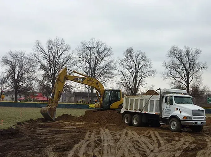 A yellow excavator is loading dirt into a dump truck.
