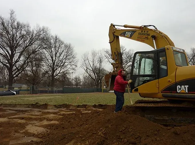 A man is standing in front of a cat excavator