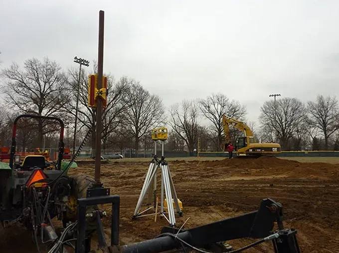 A tractor is parked next to a tripod in a dirt field.