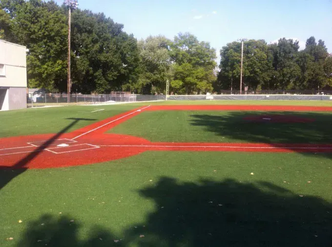 A baseball field with a red base and trees in the background