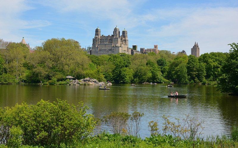 A lake with boats in it and a castle in the background.