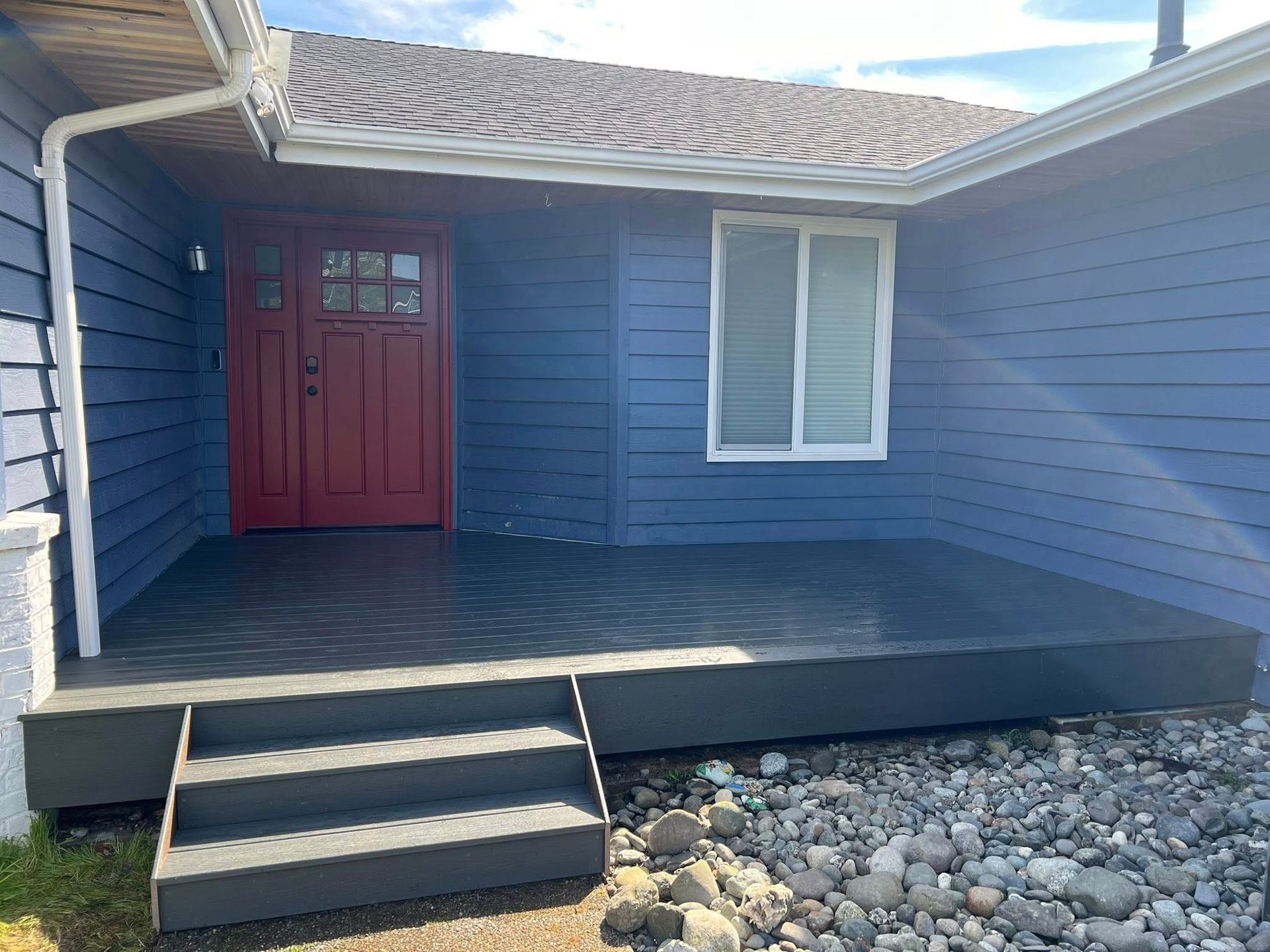 Blue house with red door and gray porch steps.