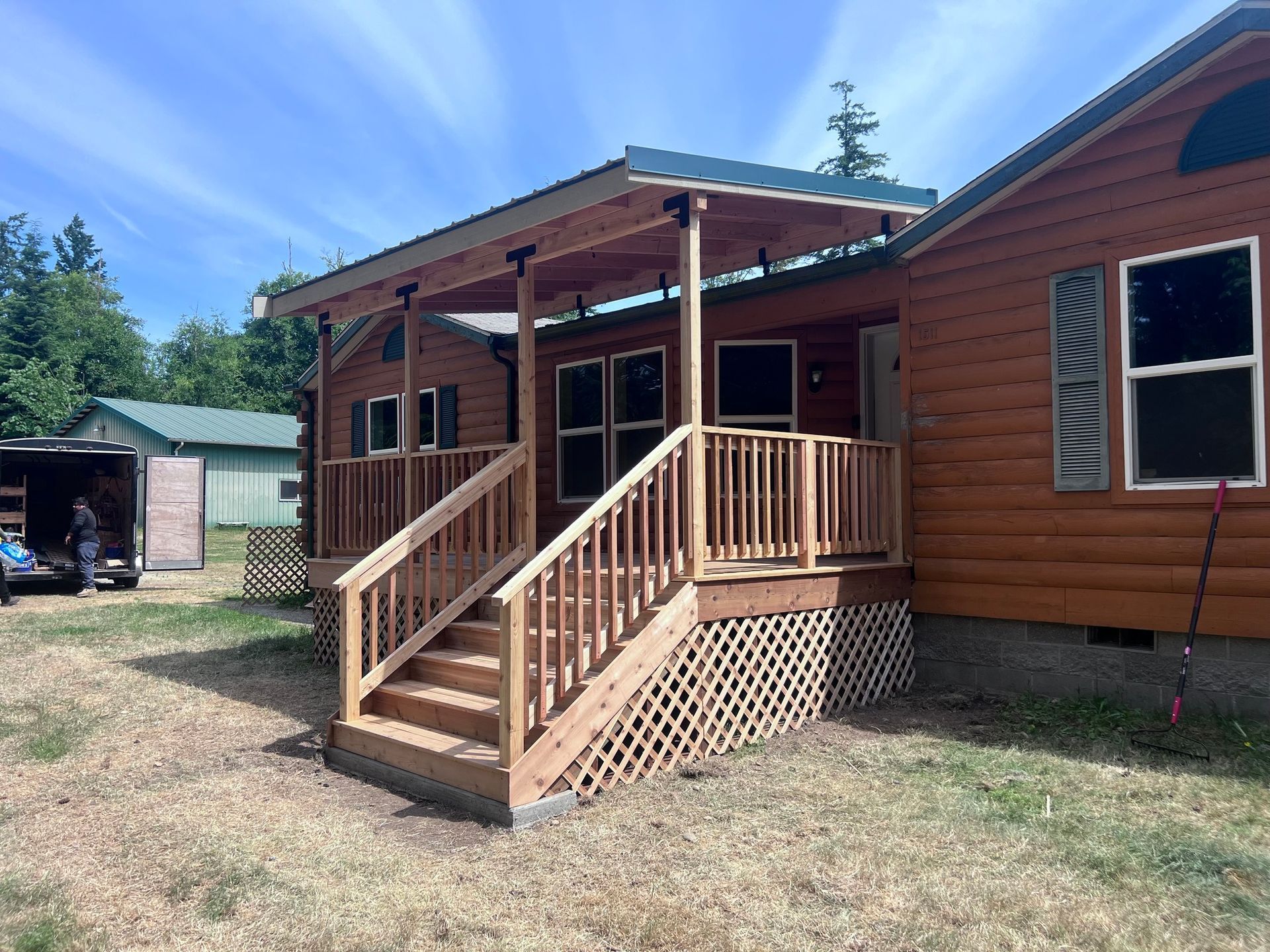Wooden cabin with a porch and stairs under a blue sky.