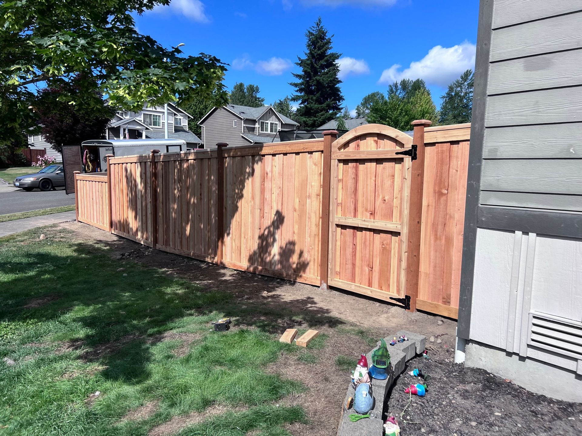 Wooden fence and gate with archway in a yard on a sunny day.