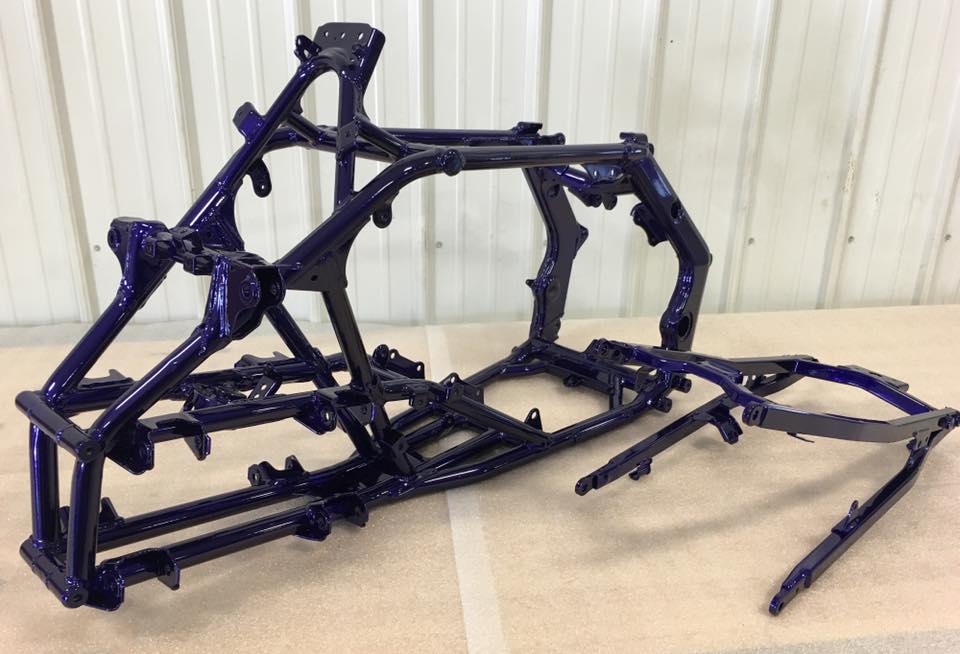 A blue atv frame is sitting on a wooden table.