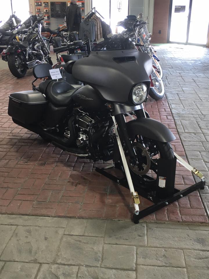 A black motorcycle is parked on a brick floor in a showroom.