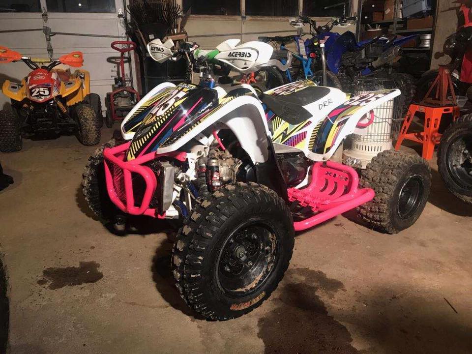 A pink and white atv is parked in a garage.