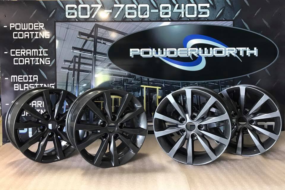 Three wheels are sitting in front of a sign that says powder coating ceramic coating and media blasting.