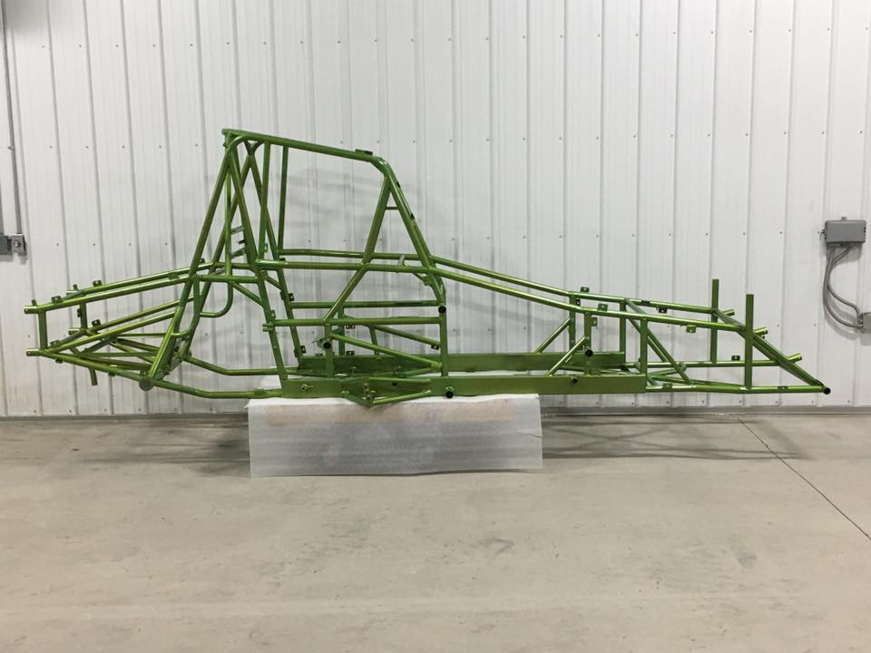 A green metal frame is sitting on top of a white block in a garage.