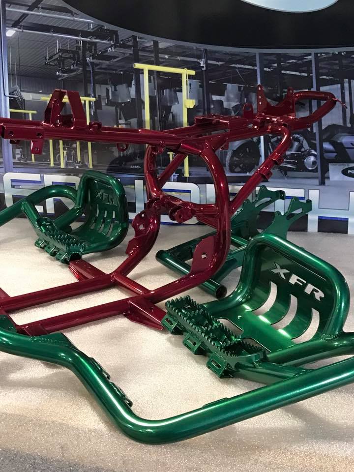 A red and green go kart is sitting on the floor in a gym.