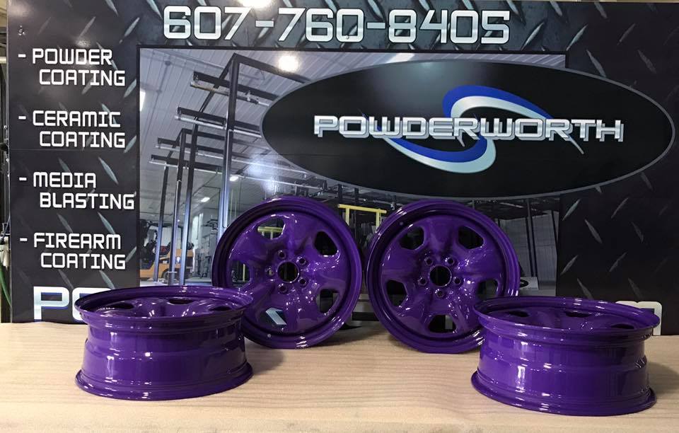 Purple wheels are sitting on a table in front of a sign that says powderworth