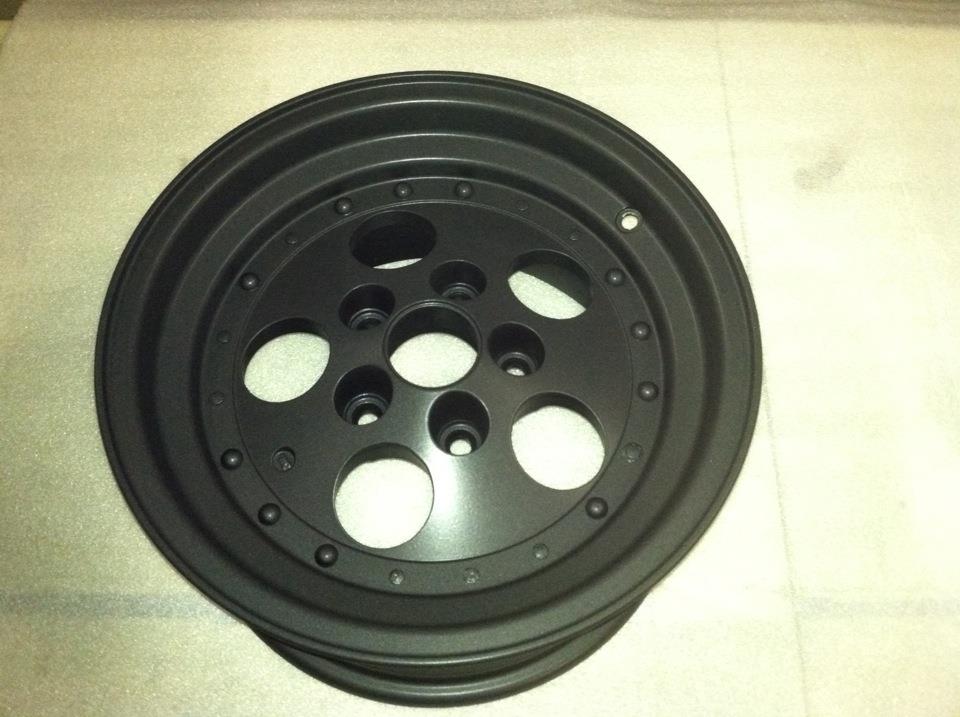 A black rim with holes in it on a white surface