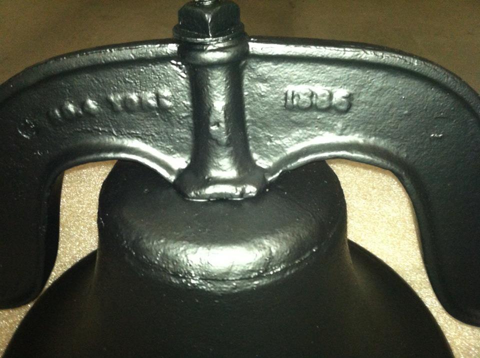 A black bell with the year 1885 on it