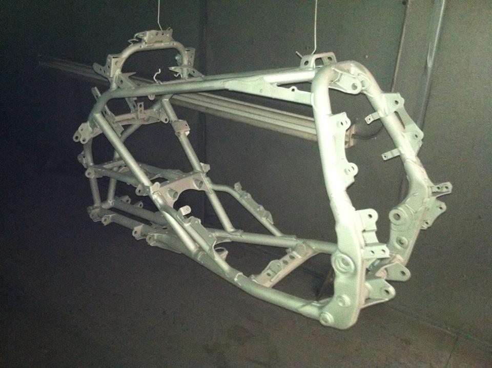 A motorcycle frame is hanging from the ceiling in a dark room