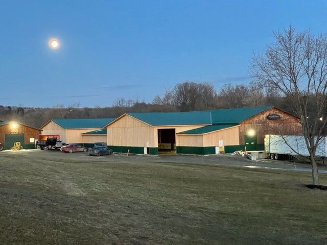 A large building with a green roof is sitting in the middle of a field.