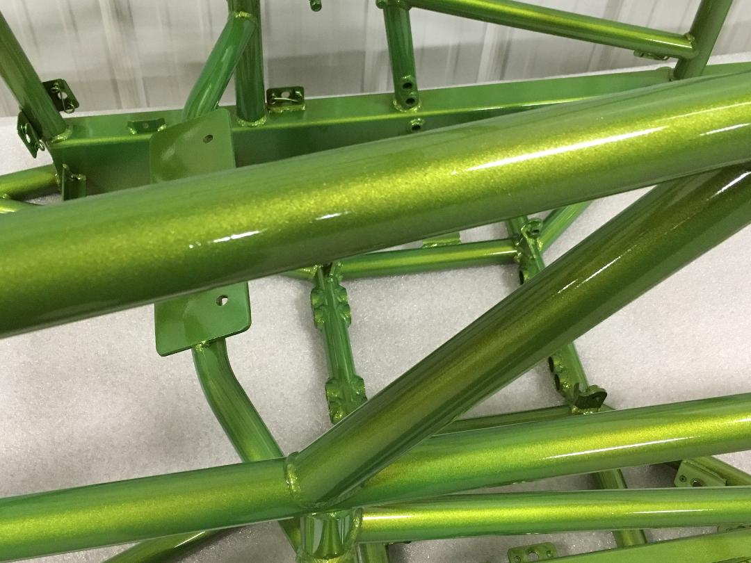 A close up of a green metal structure on a white surface.